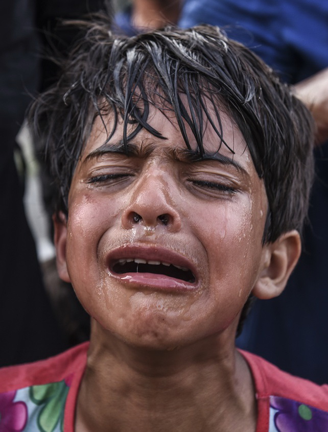 A gyerek azért sír, mert a migránsok és a magyar rendőrök közötti szerdai összecsapás során könnygázt lélegzett be (AFP)